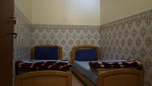 卡萨布兰卡Auberges Des Jeunes Casablanca的一间卧室配有两张带蓝色床单和壁纸的床。