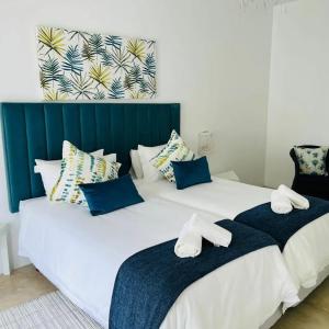 蓬塔杜欧鲁Tropicana guesthouse的卧室内的两张床,配有蓝色和白色枕头
