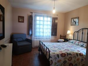 里瓦德塞利亚La Xana Ribadesella的卧室配有床、椅子和窗户。