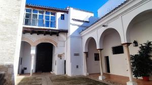 塞维利亚Preciosa Casa Renovada Centro Histórico 11 personas的两座带拱门和黑色门的白色建筑
