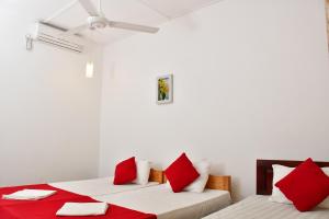尼拉瓦利Sea Way Hotel的白色客房的两张床,配有红色枕头