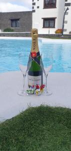 阿索马达Apartamentos Rurales Islas Canarias的一瓶葡萄酒,在游泳池畔放两杯