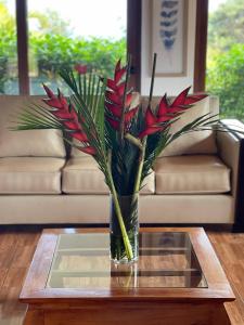 安加罗阿Teanehi Bed & Breakfast的花瓶,花朵红色,坐在桌子上