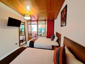 马丘比丘Inti Pacha Palace Machupicchu的酒店客房设有两张床和电视。