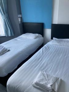 赖德Abingdon Lodge Hotel的卧室内的两张床,配有白色的床单和毛巾
