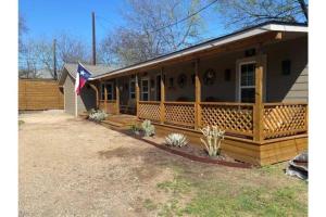 沃思堡Stockyards-Walk 1 Block to StockYards-Cowboy Cabin的一座带门廊的房屋,上面有旗帜