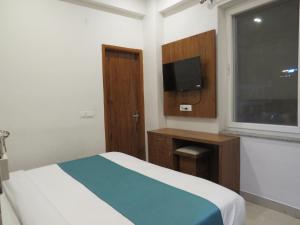 瑞诗凯诗The Namami Tapovan的一间卧室设有一张床、一台电视和一个窗口。