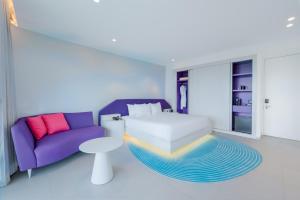 蓬塔卡纳Sunrise Miches Beach Resort, Punta Cana - All Inclusive - Adults Only的一间卧室配有一张床和一张紫色沙发