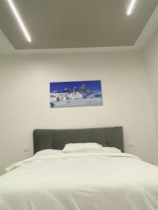 奥斯塔Appartamento Crihana的卧室配有一张白色床,墙上挂有绘画作品