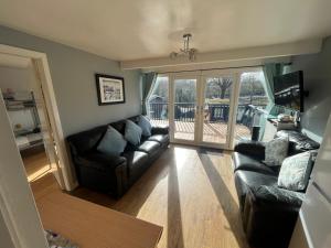 卡纳芬Cosy North Wales 2 BEDROOM Chalet的一间带真皮沙发和阳台的客厅