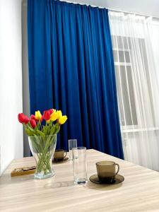 阿克套Жилой комплекс Махаббат的花瓶和蓝色窗帘的桌子