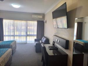 沃加沃加澳洲家园汽车旅馆 的酒店客房设有带书桌和电视的卧室。