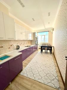 阿克套Жилой комплекс Green Park的一个带紫色橱柜和桌子的大厨房
