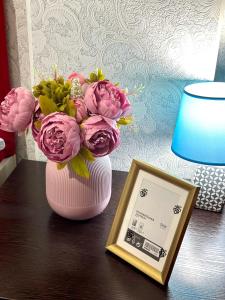 阿克套ЖК Тыныштык的粉红色的花瓶,桌子上放着一束鲜花