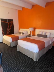 纽堡纽堡豪生酒店的橙色墙壁的酒店客房内的两张床
