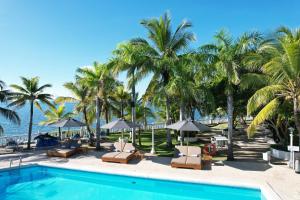 格兰德岛Hotel Cocoliso Island Resort的一个带椅子和遮阳伞的游泳池以及棕榈树