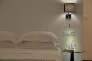 雅典雅典阿尔特尔酒店的一张带白色床单的床和一张带台灯的桌子