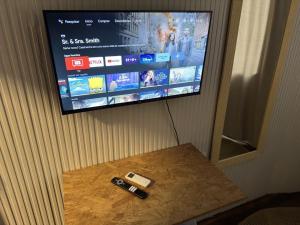 伊达贾伊Quarto Econômico com Ar Cond. e Smart Tv Netflix的挂在墙上的电视机,桌子上有两个遥控器