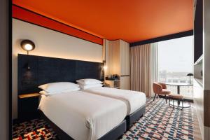 阿姆斯特丹阿姆斯特丹中央车站希尔顿逸林酒店的一间酒店客房,设有一张大床和一个大窗户