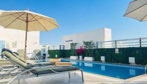 迪拜Hampton By Hilton Dubai Al Barsha的游泳池旁设有椅子和遮阳伞