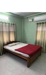古瓦哈提Suryalaxmi guest house的一间卧室配有一张床铺,床上铺有红色毯子