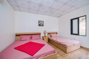 Hang SuốiWindy Garden Hostel的白色客房内的两张床和粉红色床单