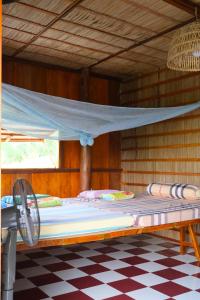 Trà VinhFarmstay Sokfarm的配有蚊帐的木制客房内的一张床位