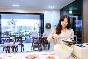 釜山Brown Dot Hotel Busan Station的一位妇女在餐馆准备食物