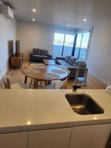 墨尔本Modern Apartment Airport Area的厨房以及带桌子和水槽的客厅。