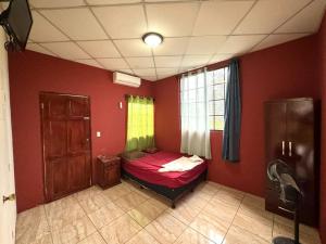 马那瓜Villalobos Hotel Managua的一间位于红色墙壁的房间的卧室,配有一张小床