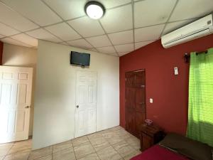 马那瓜Villalobos Hotel Managua的一间墙上配有电视的房间和一扇门