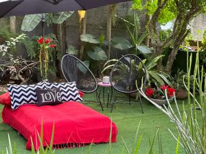 弗洛里亚诺波利斯UFSC Guest House的花园内的红色床,配有椅子和遮阳伞