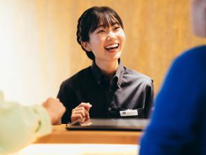 京都MIMARU SUITES KYOTO SHIJO的坐在一张桌子上,手提电脑的女人笑着