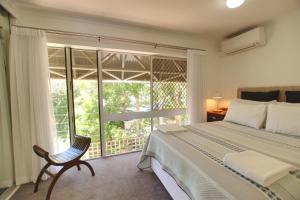 卡伦德拉Raintrees Moffat Beach的卧室配有床、椅子和窗户。