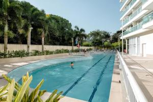 里约热内卢Suíte & Flat Premium Rio Stay - Rio Centro的在建筑物旁边的游泳池游泳的人