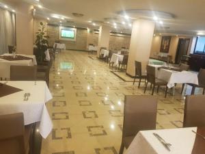 亚的斯亚贝巴Holiday Hotel Addis Ababa的一间设有白色桌椅的用餐室,铺有木地板