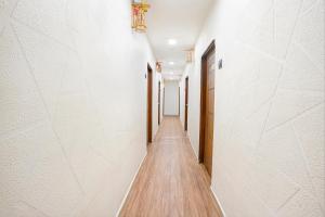 苏拉特FabHotel 7 Star的长长的走廊设有白色的墙壁和木地板