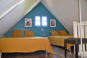 FleurimontLa Petite Kaz Dans la Savane的阁楼间设有两张床铺和蓝色的墙壁
