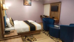 Koch BihārPoddar Residency的酒店客房,配有一张床和两张蓝色椅子