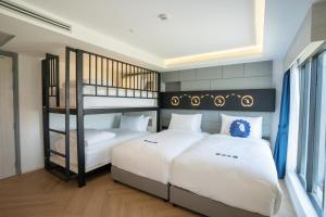 Ban Prong Phra Bat Nok (1)Kokotel Chiang Rai Airport Suites的一间卧室配有两张床和一张双层床。