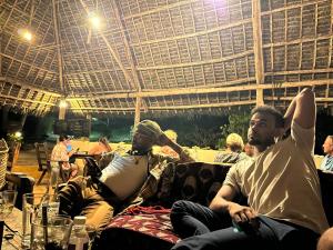 南威Sazani Beach Lodge and Tidal Lounge的一群坐在屋顶下沙发上的人