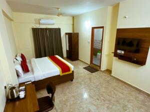 班加罗尔Sai Manyata Inn, Bangalore的一间卧室配有一张床、一张书桌和一台电视