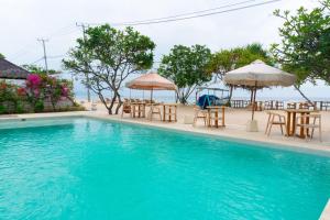 吉利美诺Ora Villas Gili Meno的一个带桌椅和遮阳伞的游泳池