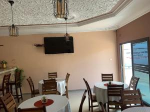 卢萨卡JUBILEE EXECUTIVE LODGE的一间设有两张桌子的用餐室和墙上的电视