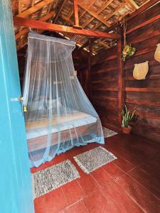 米瑞莎米丽莎鸟之家旅馆的小木屋内的一张床铺,配有蚊帐