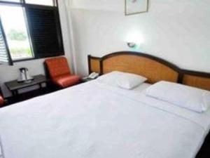 巴拉巴特Darma Agung Beach Hotel Parapat的卧室配有一张白色大床和一把椅子