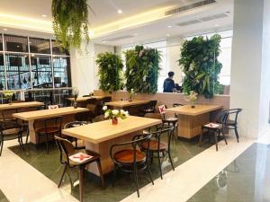 Ban Lam Rua TaekValaya Hotel Pathumthani的一间设有桌椅的餐厅,种植了植物