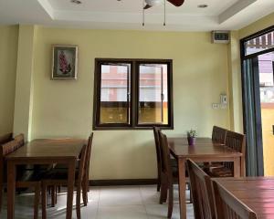 南府Ponburi Hotel的用餐室设有2张桌子和椅子以及2个窗户