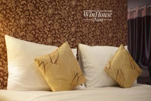 南府Winhouse Hotel的一张带白色枕头和棕色墙壁的床