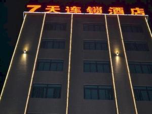 海口7 Days Inn Fucheng Wu Gongci Gaodeng East Street Binjiang Road的一座高大的白色建筑,上面有灯